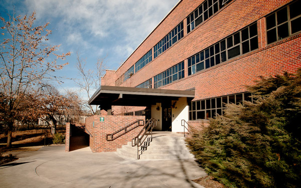 Brick residence hall with large windows, a covered entrance, and accessible ramps.