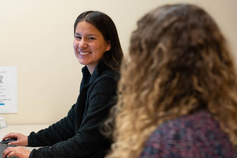 Student in background smiling, student in foreground not in focus and back of head