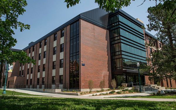 Modern brick and glass residence hall with large windows and a landscaped entrance.