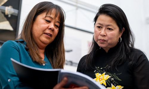 Two people look down at a book that is open