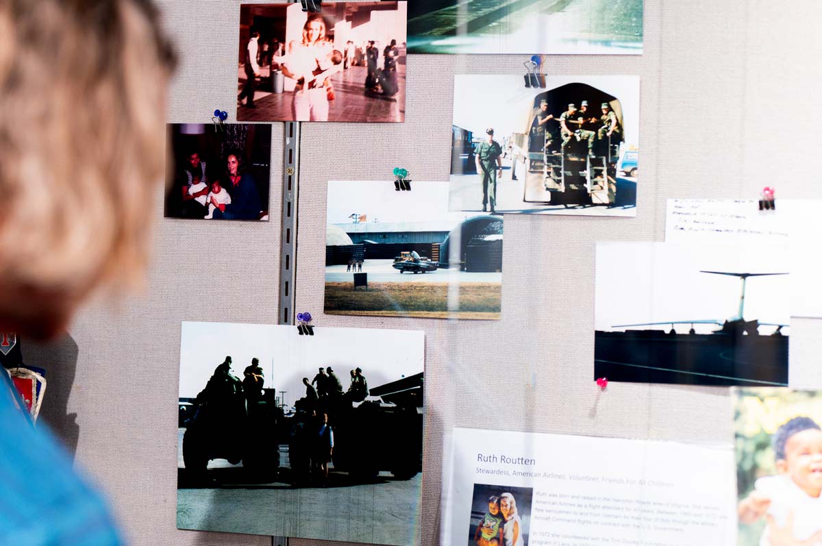 Over the shoulder of a person looking into a glass exhibit of media pieces such as newspapers and photos