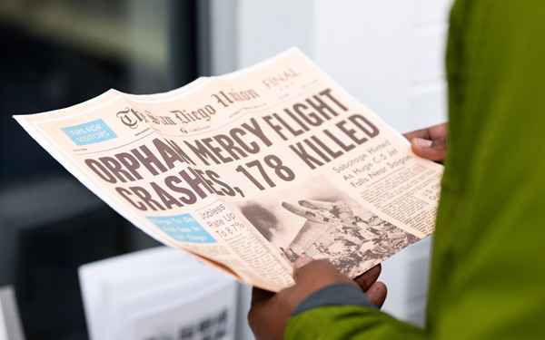 Hand hold an old newspaper from the The San Diego Union: Orphan mercy flight crashes, 178 killed