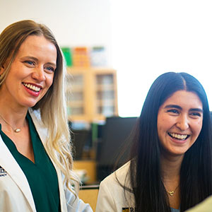 a pharmacy professor and student smile in the pharmacy lab