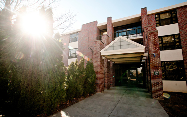A modern brick academic building with a triangular entrance overhang. 