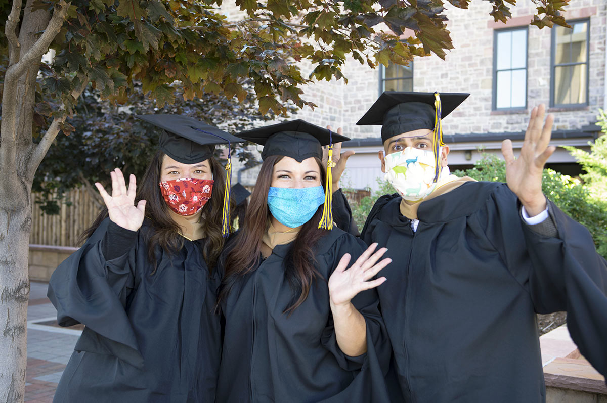 Graduates at the 2020 commencement ceremonies wave for the camera while wearing masks to protect them and others from COVID-19