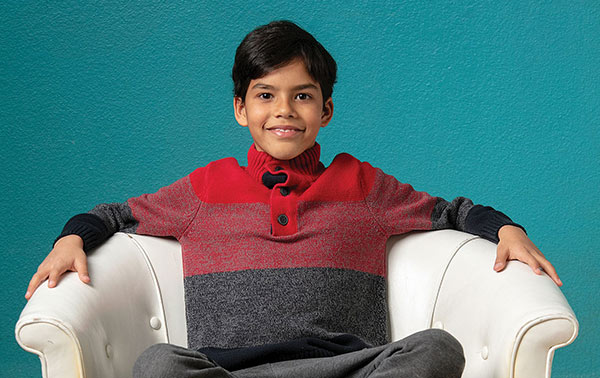 Angelo Nunez-Pulgar smiles while sitting in an armchair