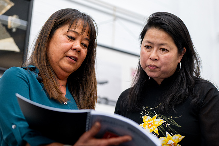 Devaki Murch and another attendee peruse the materials at her exhibit in the Regis library