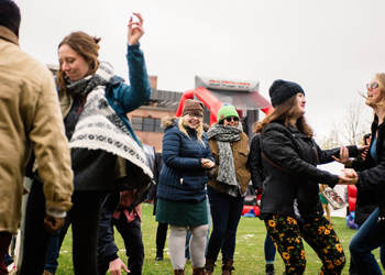 Students enjoy an outdoor campus event, dancing and socializing despite the chilly weather.